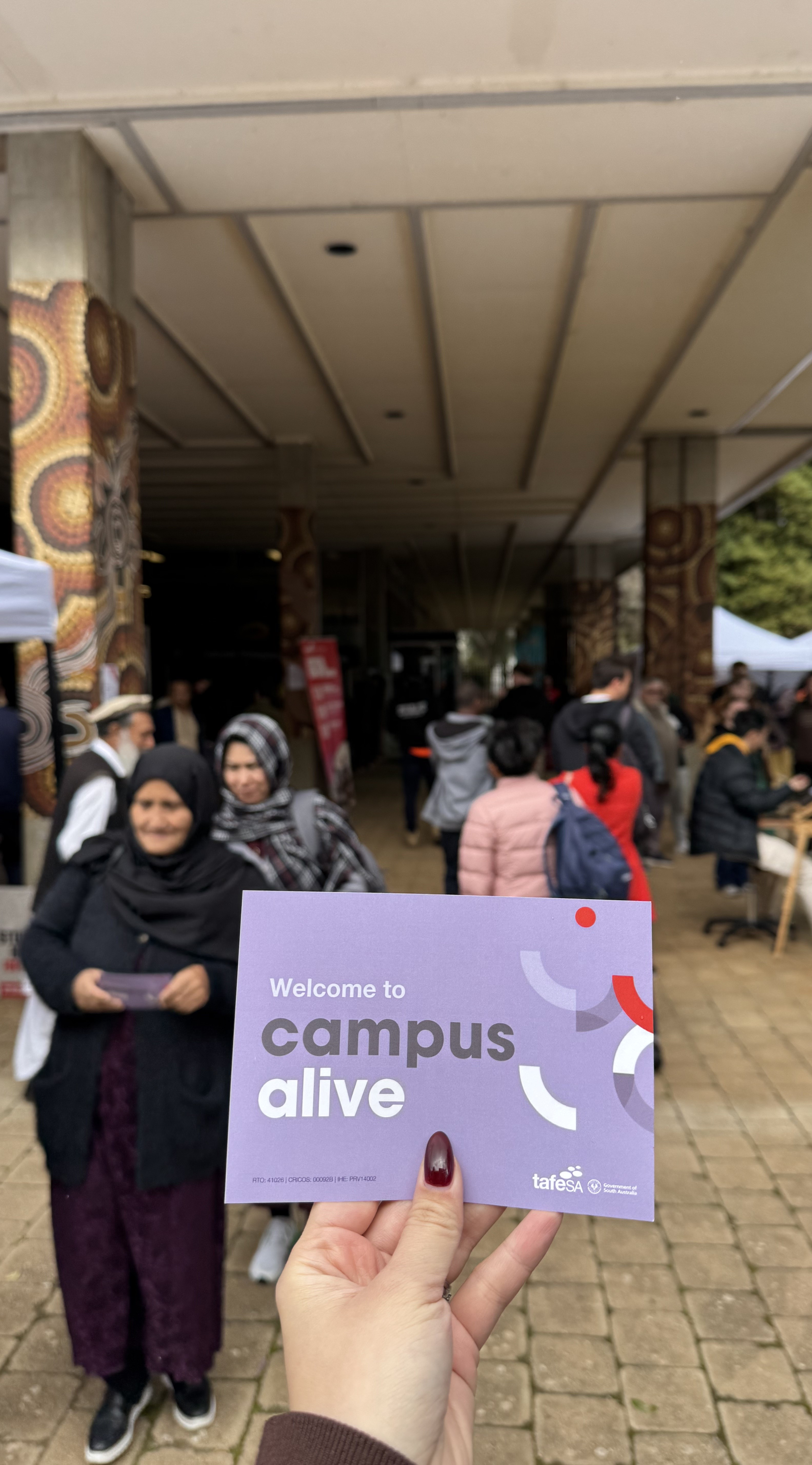 Hand holding the Campus Alive event postcard