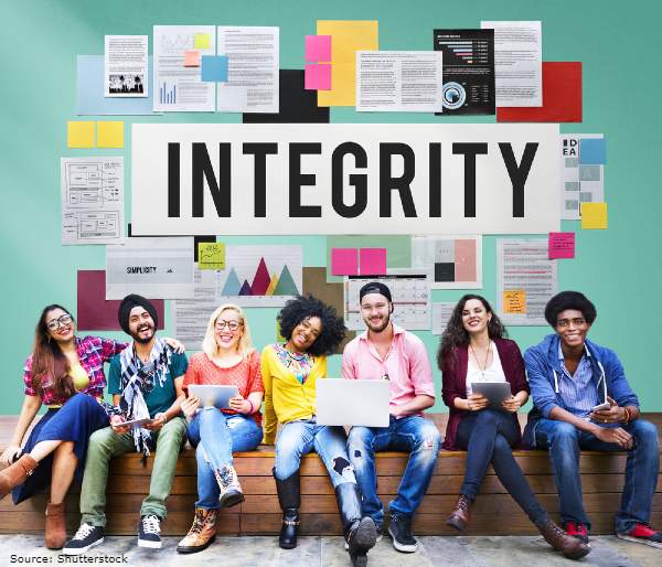 Group of happy students sitting under a banner which says integrity