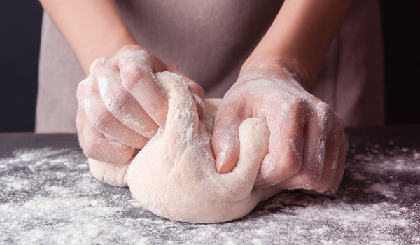 person kneading dough with flour
