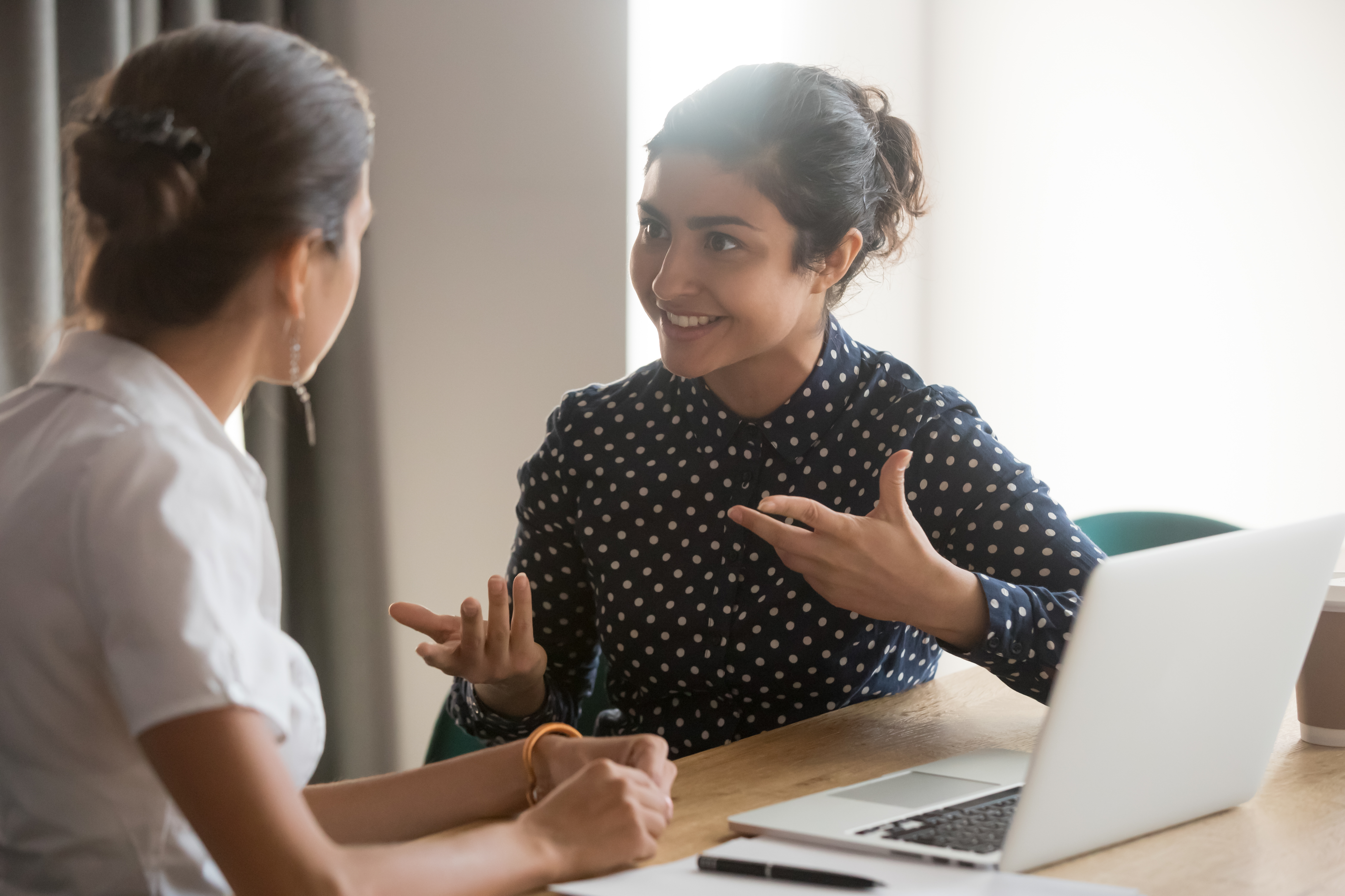 Smiling staff giving help to student at laptop